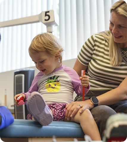 Three kids smiling together outdoors and giving thumbs up