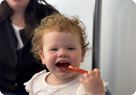 Dentist holding a model of the teeth while a young boy brushes them