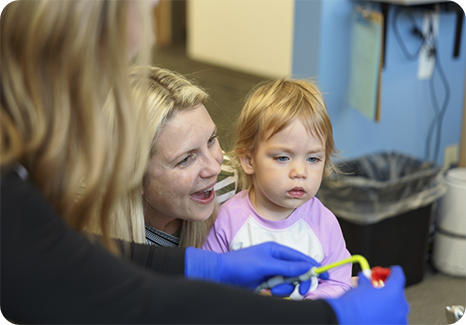 Young girl in dental chair with light pink dental bib