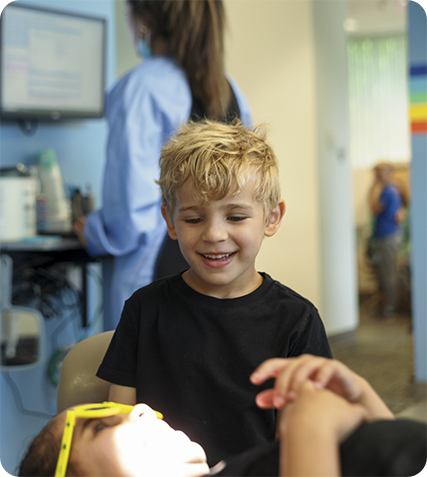 Young girl in dental chair giving a high five to her dentist