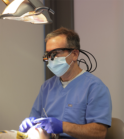 Dentist wearing personal protective equipment while treating a patient